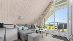 Une chambre moderne de style loft, dotée d'un lit en mezzanine, d'un canapé, d'une petite table et d'un coin cuisine.