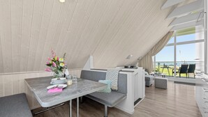 Un espace de restauration moderne avec un plafond haut, une table dressée pour deux personnes et une vue sur la mer.