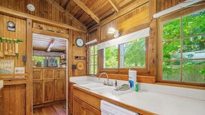 A wooden cabin interior with a kitchen area, wooden cabinets, a sink, and a dishwasher. - Cabin-style cottage w/ full kitchen, wood-burning fireplace, and full WiFi (Frankfort)