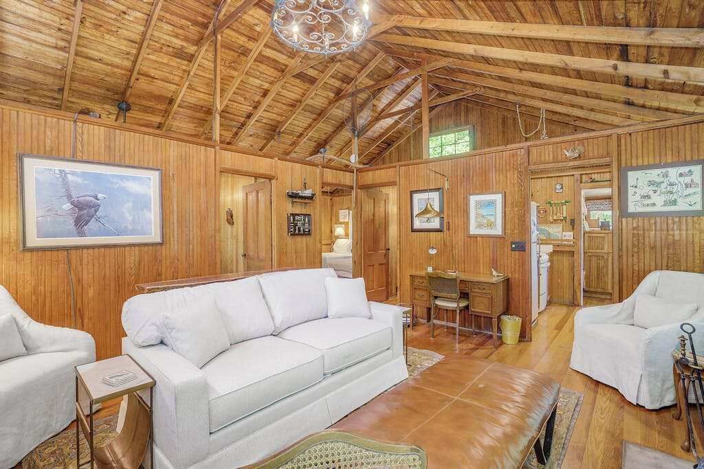 A wooden interior with a white sofa, a desk, and framed pictures on the walls.