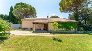 A house with a tiled roof, a small porch, and a grassy yard. - Holiday Home "Louvanna" with Luberon View, Wi-Fi, and Air Conditioning (Taillades)