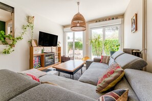 A modern living room with a sofa, a coffee table, a TV, and a hanging light fixture.