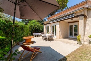 An outdoor patio with a table and chairs, a wooden chair, and a large umbrella.