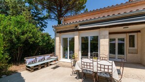 A patio with a table and chairs, a bench, and a building with large windows and a tiled roof. - Holiday Home "Louvanna" with Luberon View, Wi-Fi, and Air Conditioning (Taillades)