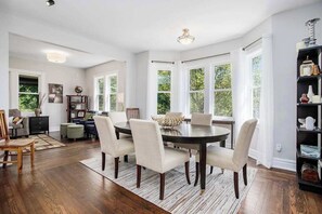 A dining area with a round table, six chairs, and a chandelier.