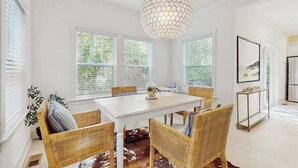 En matplats med ett vitt bord, flätade stolar, en matta av kohud och en hexagonformad hänglampa.