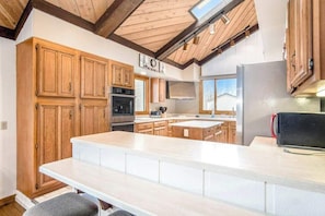 A kitchen with wooden cabinets, a large island, and a built-in oven. - Spacious Family Villa Near Beaches with Private Pool, WiFi, Firepit & Central AC (Union Pier)