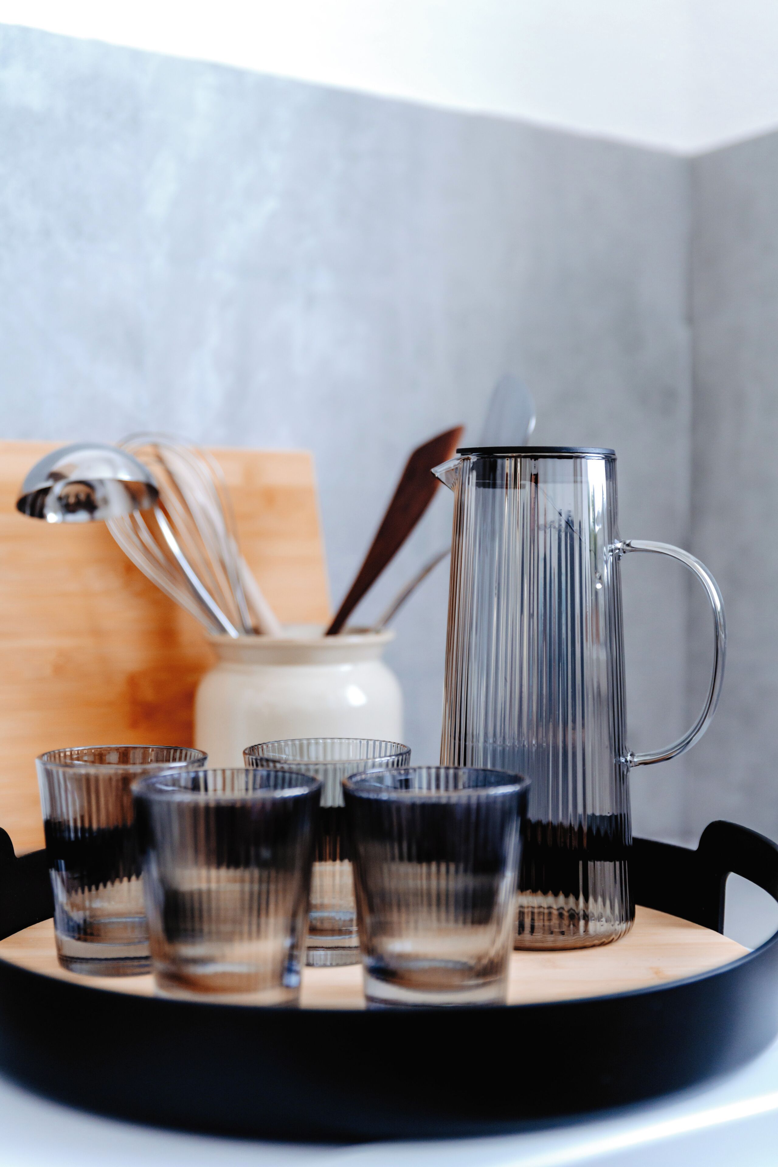 A clear glass pitcher and several glasses on a tray.
