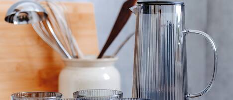 A clear glass pitcher and several glasses on a tray.