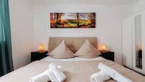 Cama bem arrumada com duas almofadas, cabeceira e duas mesas de cabeceira com abajures.