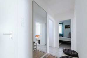 Ein modernes Interieur mit einer weißen Tür, einem Spiegel, einem Sofa, einem Bett und einem kleinen Teppich.