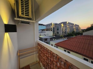 A balcony with a view of buildings, a staircase, and an air conditioning unit.