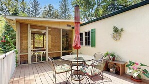 A deck with a round table and chairs, a covered umbrella, and potted plants. - Dog-Friendly Home with Enclosed Yard & Free High-Speed WiFi - Great Location (Union Pier)