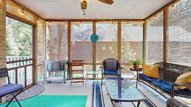 A covered outdoor area with a ceiling fan, a grill, seating, and large windows. - Dog-Friendly Home with Enclosed Yard & Free High-Speed WiFi - Great Location (Union Pier)
