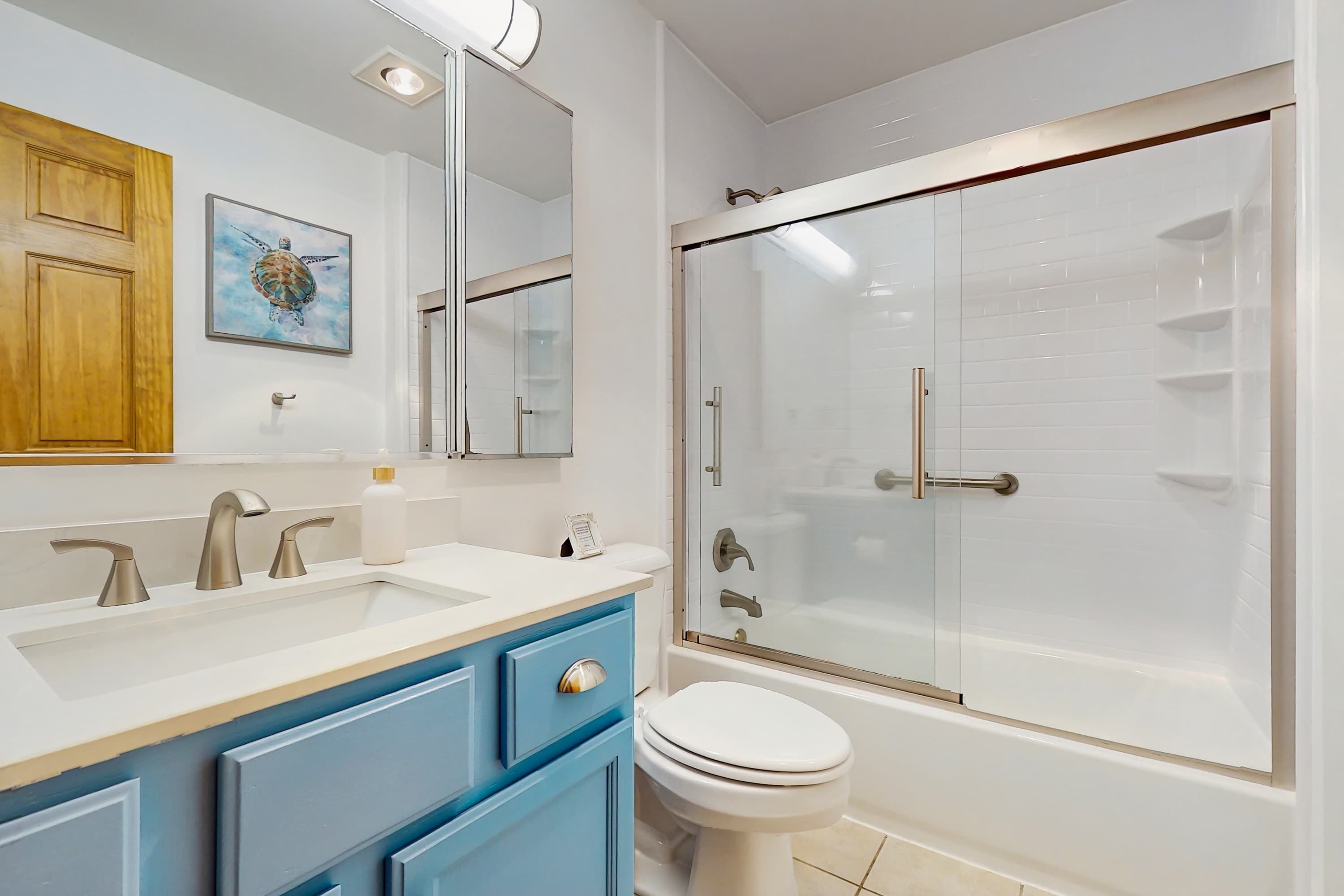 Un baño con lavamanos doble, inodoro y ducha con mampara de vidrio.
