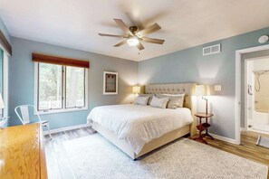 Ein Schlafzimmer mit einem Bett, Deckenventilator, Nachttischlampen und einem Fenster.