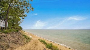 A beach with a sandy path, a white structure, and a clear sky. - The Oasis at Forest Beach | Updated house in New Buffalo with shared amenities (New Buffalo)