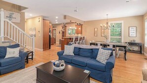 A spacious living room with a blue sofa, a coffee table, and a staircase leading to another level. - The Oasis at Forest Beach | Updated house in New Buffalo with shared amenities (New Buffalo)