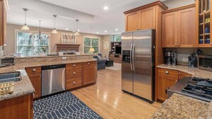 A modern kitchen with wooden cabinets, stainless steel appliances, and pendant lighting. - The Oasis at Forest Beach | Updated house in New Buffalo with shared amenities (New Buffalo)