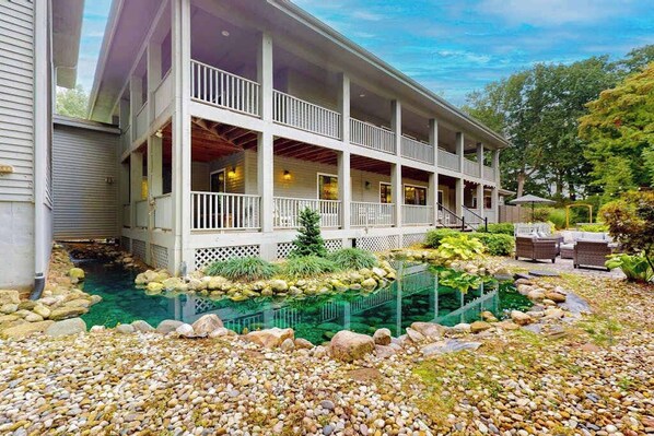 A two-story building with a covered porch, a swimming pool, and a garden area with rocks and plants. - Spacious home with game room, hot tub, fireplace, fast WiFi & home theater (St. Joseph)