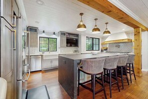 A modern kitchen with a central island, bar stools, pendant lights, and a view of the outdoors. - Spacious home with game room, hot tub, fireplace, fast WiFi & home theater (St. Joseph)