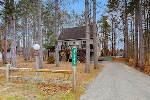 A pathway leading to a house surrounded by tall trees. - Spacious Home with deck, grill  & added Crystal Mountain Amenities (Thompsonville)