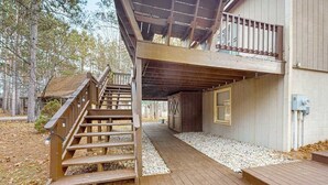 Eine Holzterrasse führt zu einer Hütte mit Treppe und überdachtem Bereich.
