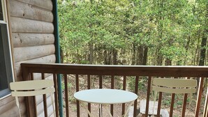 Eine Holzterrasse mit einem weißen Tisch und zwei Stühlen.