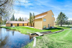 A modern building with a sloped roof, a small pond, and a grassy area with a bench. - Beautiful 2B/2B Harbor Springs Condo Just 6 Mi to Lake Michigan! (Harbor Springs)