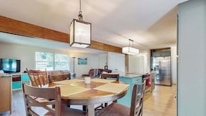A modern kitchen with a dining area, wooden cabinets, and a large island. - Peaceful Home with Firepit, Gas Grill, WIFI,  Private W&D & Nearby Beach Access (St. Joseph)