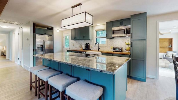 A modern kitchen with a central island, bar stools, and a pendant light. - Peaceful Home with Firepit, Gas Grill, WIFI,  Private W&D & Nearby Beach Access (St. Joseph)