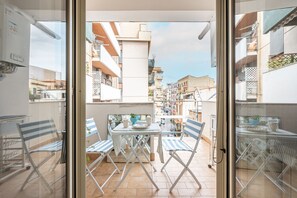 A balcony with a table and chairs, a view of the cityscape, and a glass door. - D'Ossuna Central Home by Wonderful Italy (Palermo)