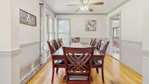 A dining area with a wooden table and chairs, a ceiling fan, and a framed quote on the wall. - Lovely home with hot tub, pool, two kitchens, enclosed backyard, firepit & grill (New Buffalo)