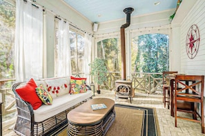 A sunroom with a sofa, a table, a fireplace, and a view of the outdoors. - Luxurious home with woodstove, fireplace, & screened porch - walk everywhere (Saugatuck)