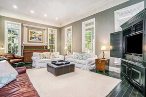 A living room with a fireplace, a television, and a large window. - Luxurious home with woodstove, fireplace, & screened porch - walk everywhere (Saugatuck)
