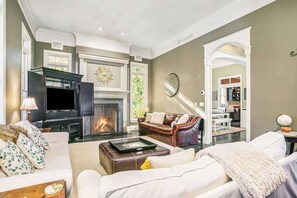 A living room with a fireplace, leather sofa, and a television. - Luxurious home with woodstove, fireplace, & screened porch - walk everywhere (Saugatuck)