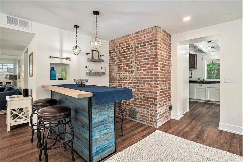 A kitchen with a brick accent wall, wooden bar stools, and pendant lighting.