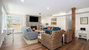 Ein Wohnzimmer mit Kamin, einem blauen Sofa, Korbstühlen und einer Wand mit Steinverkleidung.