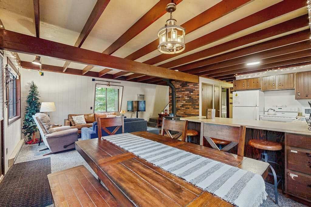 A spacious living area with a wooden dining table, a fireplace, and a kitchen with wooden cabinets.