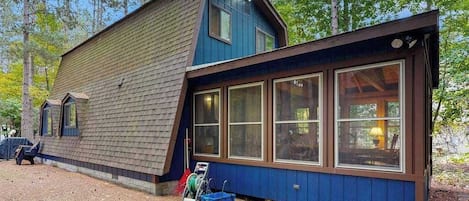 A cabin with a sloped roof, large windows, and a wooden exterior.
