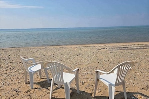 A beach with three white plastic chairs facing the sea. - Rustic A-Frame Retreat on Grand Traverse Bay w/ beach, wifi, fire pit & grill (Williamsburg)