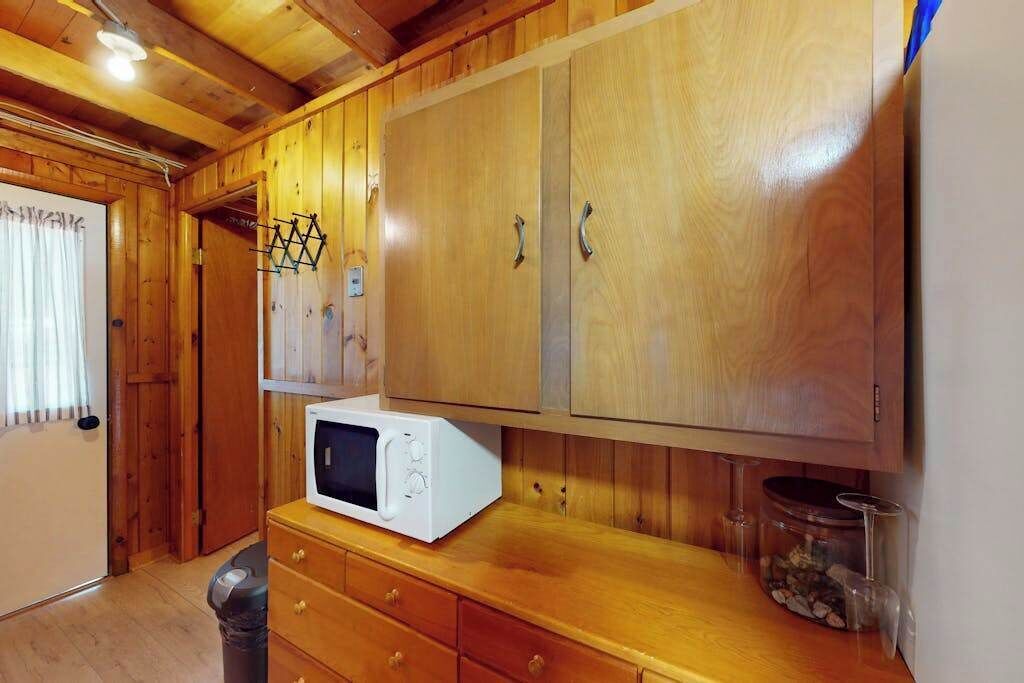Un intérieur en bois avec un four à micro-ondes posé sur un comptoir en bois, des placards et une poubelle.
