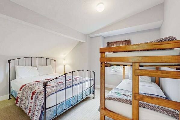 A bedroom with a bunk bed, a single bed, and a window with curtains.