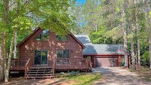 A log cabin with a porch, a garage, and a deck. - Resort home with private indoor hot tub, game room, firepit, bikes, Ping-Pong (Thompsonville)