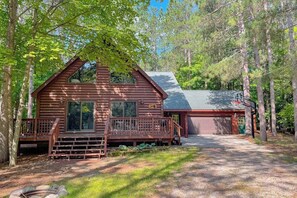 A log cabin with a porch, a garage, and a deck. - Resort home with private indoor hot tub, game room, firepit, bikes, Ping-Pong (Thompsonville)