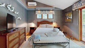 Ein Schlafzimmer mit Bett, Kommode, Fernseher und Kunstwerken.