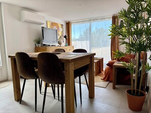 Ein Essbereich mit Holztisch, Stühlen, einem Fernseher und einem Blumentopf.