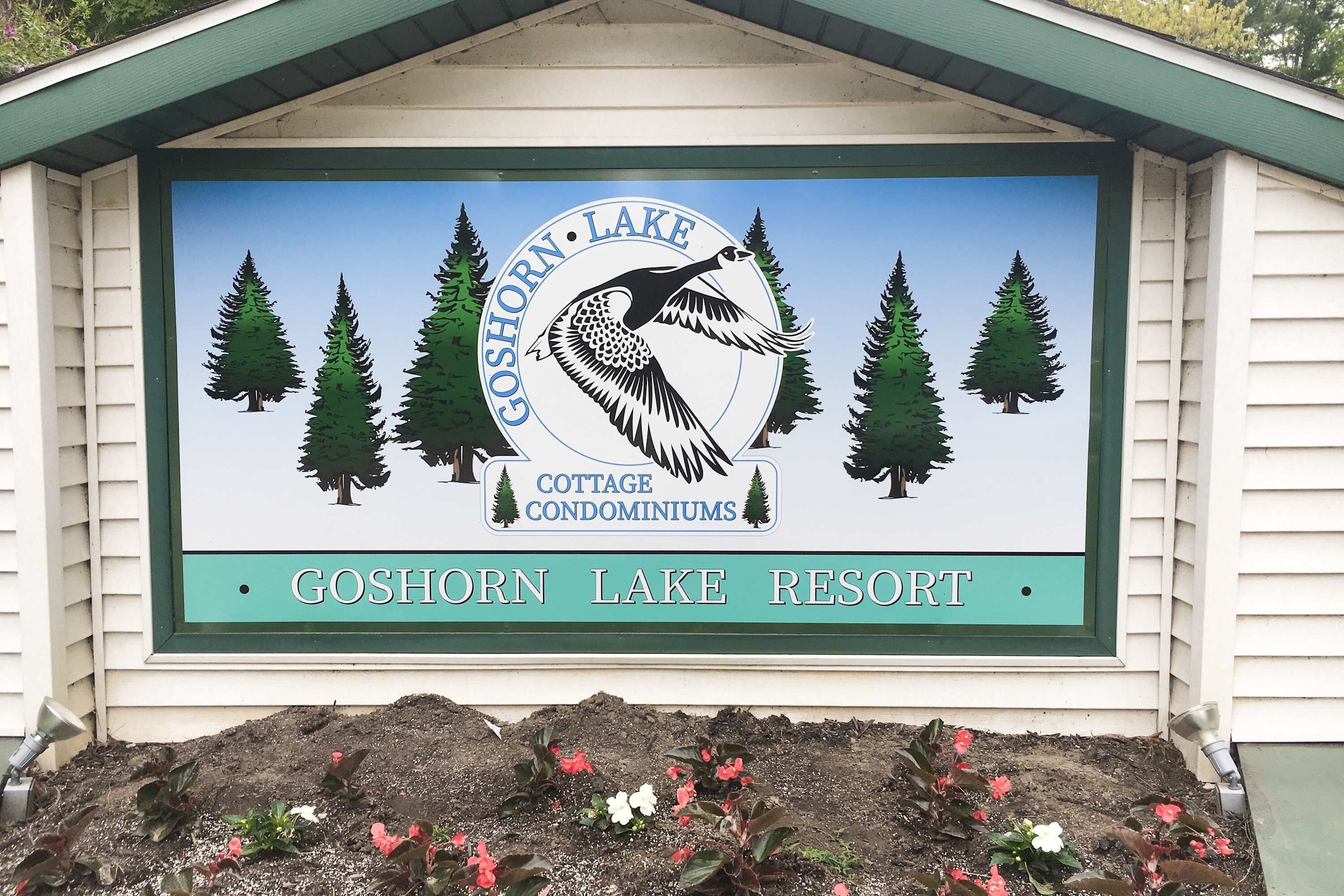 Opastekyltti, jossa on kuva lintuun ja puihin, ja jossa lukee ”Goshorn Lake Resort”.