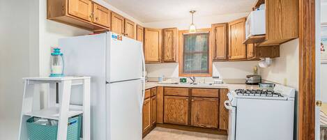A kitchen with wooden cabinets, a white refrigerator, a stove, and a sink.