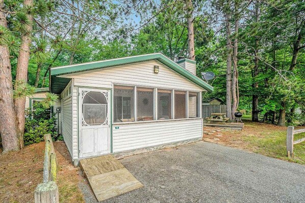 A small cabin with a green roof, a front door, and a window.